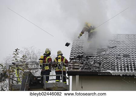 "Firefighters wearing breathing equipment while extinguishing a roof fire, removing the roof tiles to access the roof, Aichwald, Baden-Wurttemberg, Germany, Europe" View Large Photo Image Stock Image - "Firefighters wearing breathing equipment while extinguishing a roof fire, removing the roof tiles to access the roof, Aichwald, Baden-Wurttemberg, Germany, Europe". Fotosearch
