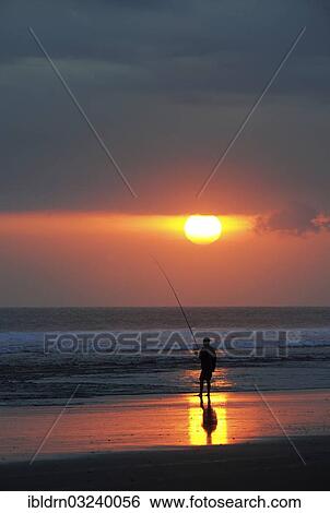 Stock Photograph - "Fisherman fishing at sunset on the beach, Tanah Lot, Bali, Indonesia, Asia". Fotosearch
