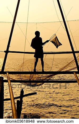 "Fisherman holding a landing net in front of a Chinese fishing net at sunrise, Vembanad lake, Kerala, India, Asia" View Large Photo Image Stock Photo - "Fisherman holding a landing net in front of a Chinese fishing net at sunrise, Vembanad lake, Kerala, India, Asia". Fotosearch