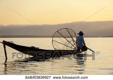 "Fisherman in the evening light, with a traditional basket, sitting on a canoe, sunset at Inle Lake, Shan State, Myanmar, Asia" View Large Photo Image Stock Photo - "Fisherman in the evening light, with a traditional basket, sitting on a canoe, sunset at Inle Lake, Shan State, Myanmar, Asia". Fotosearch
