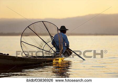 "Fisherman in the evening light, with a traditional basket, sitting on a canoe, sunset at Inle Lake, Shan State, Myanmar, Asia" View Large Photo Image Stock Photograph - "Fisherman in the evening light, with a traditional basket, sitting on a canoe, sunset at Inle Lake, Shan State, Myanmar, Asia". Fotosearch
