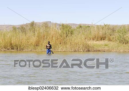 Stock Image - "Fisherman standing in the Oranje, Orange River, border river between Namibia and South Africa". Fotosearch