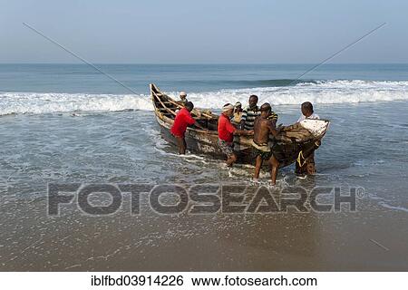 Stock Photograph - "Fishermen pushing a boat onto the beach, Varkala, Kerala, India, Asia". Fotosearch