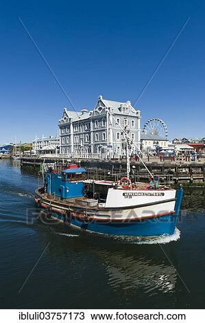 Stock Image - "Fishing cutter in front of the African Trading Port building, Victoria and Alfred Waterfront, Cape Town, Western Cape, South Africa, Africa". Fotosearch