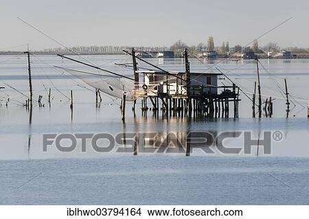 Picture - "Fishing hut in a lagoon, with reflections, Po River Delta, Comacchio, Emilia-Romagna, Italy, Europe". Fotosearch