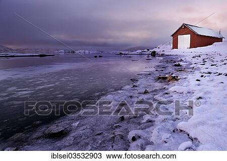 Stock Image - "Fishing hut on the ice-covered shore of a fjord in the evening light, Tromso, â€ªTroms, Northern Norway, Norway, Europe". Fotosearch