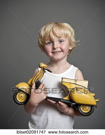 "Five-year-old boy holding a toy Vespa scooter, gift, happy face" View Large Photo Image Stock Photo - "Five-year-old boy holding a toy Vespa scooter, gift, happy face". Fotosearch