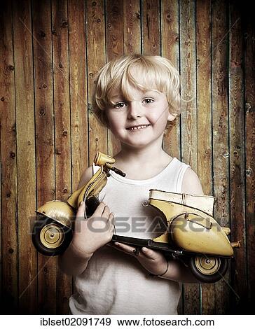 Stock Photo - "Five-year-old boy holding a toy Vespa scooter, gift, happy face". Fotosearch