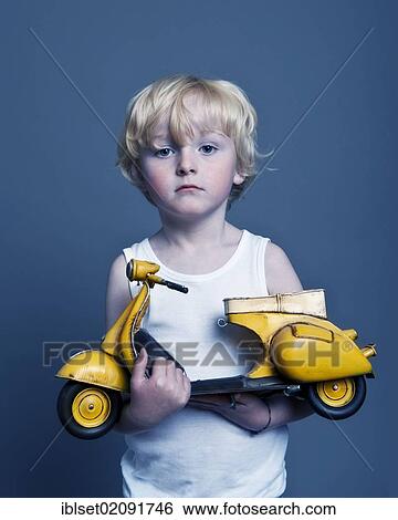 "Five-year-old boy holding a toy Vespa scooter, gift, sad face" View Large Photo Image Stock Photograph - "Five-year-old boy holding a toy Vespa scooter, gift, sad face". Fotosearch