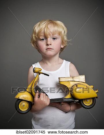 Stock Photography - "Five-year-old boy holding a toy Vespa scooter, gift, sad face". Fotosearch