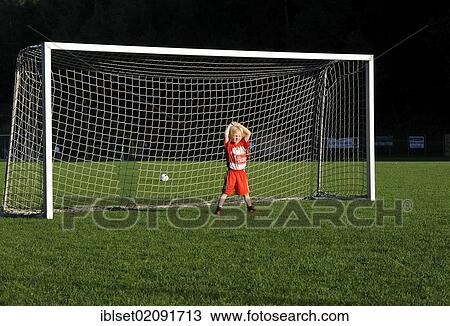 Stock Image - "Five-year-old boy wearing a FC Bayern Munich soccer dress, boredly standing in a soccer goal". Fotosearch