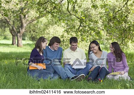 "Five young students sitting on grass doing teamwork with a laptop, Hannover, Lower Saxony, Germany, Europe" View Large Photo Image Stock Photograph - "Five young students sitting on grass doing teamwork with a laptop, Hannover, Lower Saxony, Germany, Europe". Fotosearch