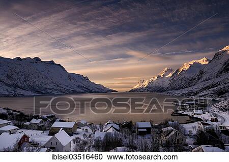 Stock Image - "Fjord with small town in the evening light, Ersfjord, Tromso, â€ªTroms, Northern Norway, Norway, Europe". Fotosearch