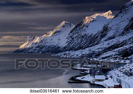 Stock Image - "Fjord with small town in the evening light, Ersfjord, Tromso, â€ªTroms, Northern Norway, Norway, Europe". Fotosearch