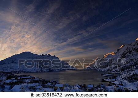 Stock Image - "Fjord with small town in the evening light, Ersfjord, Tromso, â€ªTroms, Northern Norway, Norway, Europe". Fotosearch