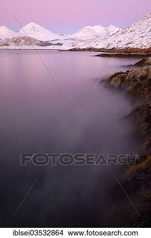 Picture - "Fjord with stones in front of a mountain range in the evening light, Tromso, â€ªTroms, Northern Norway, Norway, Europe". Fotosearch
