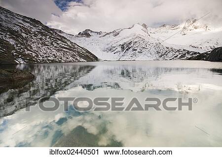 "Foggy atmosphere at Unterer Gerlossee lake with mountains Wildgerlosspitze, Hahnenkamm and Reichenspitze at back, Zillertal valley, Tyrol, Austria, Europe" View Large Photo Image Stock Image - "Foggy atmosphere at Unterer Gerlossee lake with mountains Wildgerlosspitze, Hahnenkamm and Reichenspitze at back, Zillertal valley, Tyrol, Austria, Europe". Fotosearch