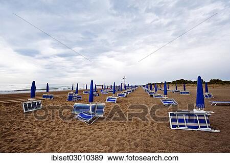 "Folded deck chairs and parasols on a beach by the sea with rain clouds, Cavallino, Jesolo, Venedig, Italy, Europe" View Large Photo Image Stock Photo - "Folded deck chairs and parasols on a beach by the sea with rain clouds, Cavallino, Jesolo, Venedig, Italy, Europe". Fotosearch
