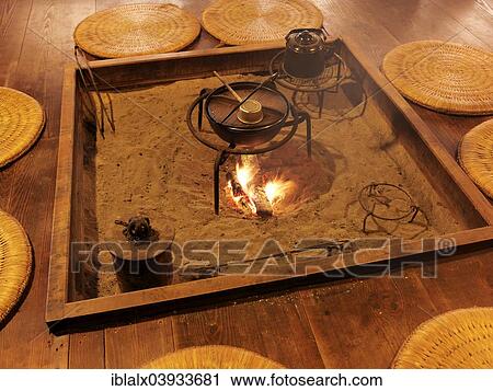 Food Being Cooked On Fire With Straw Cushions Around The Fire Pit