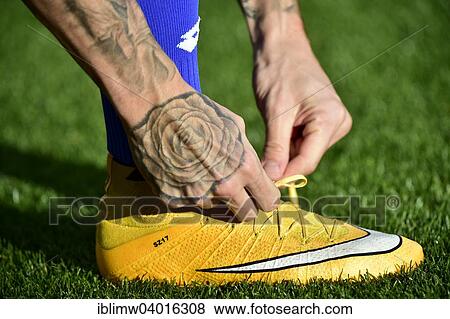 "Football player tying the laces of his soccer shoes, tattoo" View Large Photo Image Stock Photo - "Football player tying the laces of his soccer shoes, tattoo". Fotosearch