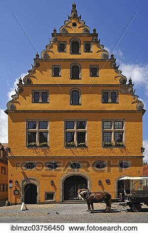 Stock Image - "Former municipal granary with a steep pitched roof and Baroque voluted gable, early 17th Century, in front a horse carriage, Dinkelsbuhl, Middle Franconia, Bavaria, Germany, Europe". Fotosearch