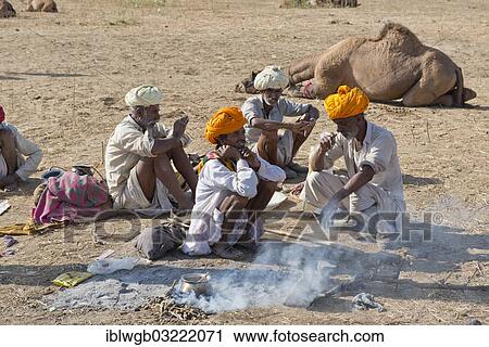 "Four elderly Indian men with turbans and wearing the traditional Dhoti garment squatting on the ground, food is being prepared over an open fire, Pushkar Camel Fair, Pushkar, Rajasthan, India, Asia" View Large Photo Image Stock Image - "Four elderly Indian men with turbans and wearing the traditional Dhoti garment squatting on the ground, food is being prepared over an open fire, Pushkar Camel Fair, Pushkar, Rajasthan, India, Asia". Fotosearch