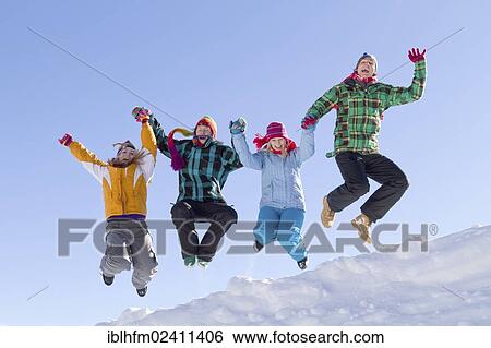 "Four young people wearing colourful winter clothes jumping over a snow-covered ridge, Flachau, Salzburg, Austria, Europe" View Large Photo Image Stock Photograph - "Four young people wearing colourful winter clothes jumping over a snow-covered ridge, Flachau, Salzburg, Austria, Europe". Fotosearch