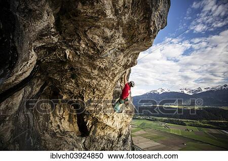 Stock Image - "Freeclimber with helmet climbing on a rock face, Martinswand, gallery, Innsbruck, Tyrol, Austria, Europe". Fotosearch