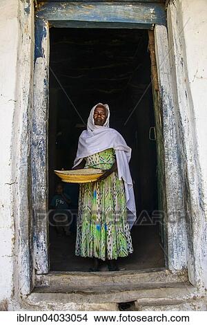 Picture - "Friendly old woman standing with a basket of corn in a door frame, near Keren, Eritrea, Africa". Fotosearch