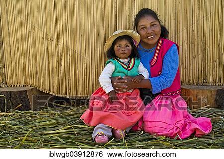 "Friendly woman and a girl of the Uro Indians wearing traditional dress sitting in front of a reed hut, floating islands made of totora reeds, Lake Titicaca, southern Peru, Peru, South America" View Large Photo Image Stock Photograph - "Friendly woman and a girl of the Uro Indians wearing traditional dress sitting in front of a reed hut, floating islands made of totora reeds, Lake Titicaca, southern Peru, Peru, South America". Fotosearch