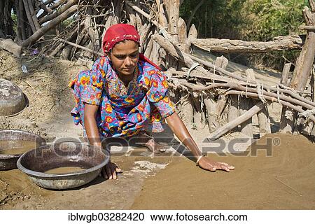 "Friendly young woman in traditional dress plastering the floor of a courtyard with a mixture of water, sand and cow dung, Rann of Kutch, Gujarat, India, Asia" View Large Photo Image Stock Image - "Friendly young woman in traditional dress plastering the floor of a courtyard with a mixture of water, sand and cow dung, Rann of Kutch, Gujarat, India, Asia". Fotosearch