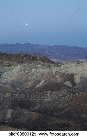 Stock Photography - "Full moon over the Panamint Range and the Death Valley at dawn, seen from Zabriskie Point, the badlands of Gower Gulch in the foreground, Death Valley National Park, California, USA". Fotosearch