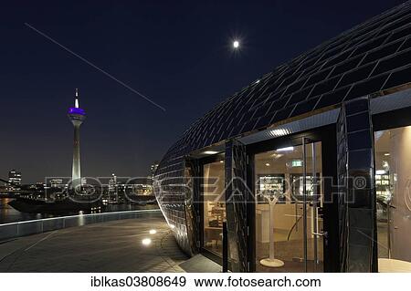 Stock Photo - "Futuristic pavilion with a mirrored facade, Hyatt Regency hotel bar """"Pebble's"""" at the blue hour, Media Harbour, Dusseldorf, North Rhine-Westphalia, Germany, Europe". Fotosearch