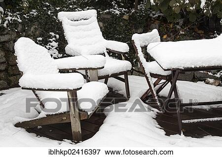 Stock Photo - Garden chairs and a table covered with snow. Fotosearch