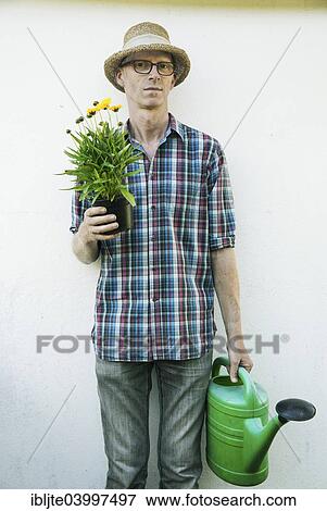 "Gardener, garden plot holder, holding a flower and a watering can, Germany, Europe" View Large Photo Image Stock Photo - "Gardener, garden plot holder, holding a flower and a watering can, Germany, Europe". Fotosearch