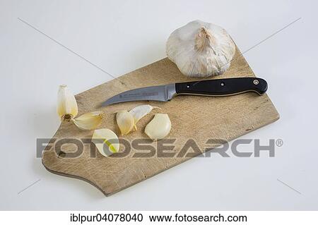 Stock Image - Garlic on a kitchen board with knife. Fotosearch
