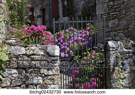 Stock Image - "Gate, stone wall, flowers, Turenne, labelled Les Plus Beaux Villages de France, Correze, Limousin, France, Europe". Fotosearch