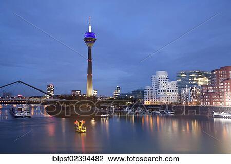 Stock Image - "Gehry buildings at dusk, Neuer Zollhof building complex and the Rheinturm tower, Medienhafen district, Duesseldorf, North Rhine-Westphalia, Germany, Europe". Fotosearch