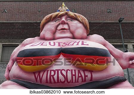 Stock Image - "German Chancellor Merkel as a fat Buddha, political caricature about the German economy, papier-mache figure for the Rose Monday parade, Carnival, Dusseldorf, North Rhine-Westphalia, Germany, Europe". Fotosearch