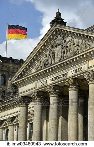 Stock Image - "German flag flying on the Reichstag building, parliament, Bundestag, lettering on the tympanum above the main portal """"Dem Deutschen Volke"""", German for """"to the German people"""", Government District, Berlin, Berlin, Germany, Europe". Fotosearch