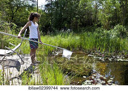 Picture - "Girl, 11, fishing with a net in a garden pond, Austria, Europe". Fotosearch