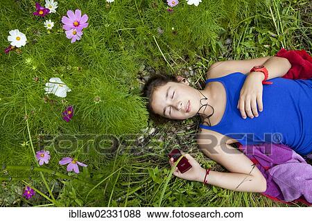 "Girl, 11 years, lying in a flower meadow listening to music on an MP3 player" View Large Photo Image Stock Photo - "Girl, 11 years, lying in a flower meadow listening to music on an MP3 player". Fotosearch