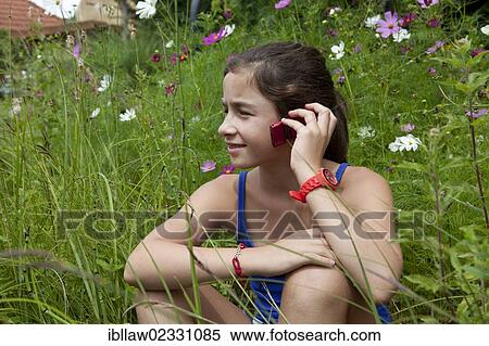 "Girl, 11 years, sitting in a flower meadow talking on a mobile phone" View Large Photo Image Stock Photography - "Girl, 11 years, sitting in a flower meadow talking on a mobile phone". Fotosearch