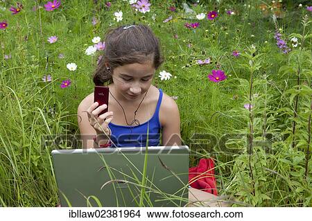 "Girl, 11 years, sitting on a meadow with a laptop computer, listening to music" View Large Photo Image Picture - "Girl, 11 years, sitting on a meadow with a laptop computer, listening to music". Fotosearch