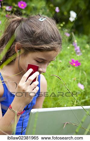 Stock Photography - "Girl, 11 years, sitting on a meadow with a laptop computer, listening to music". Fotosearch