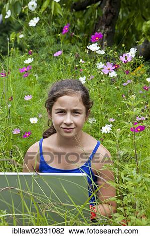 "Girl, 11 years, working on a laptop computer, notebook, sitting in a flower meadow" View Large Photo Image Stock Image - "Girl, 11 years, working on a laptop computer, notebook, sitting in a flower meadow". Fotosearch