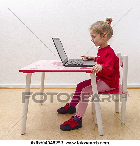 Stock Image - "Girl, 3 years, sitting at a table, using a laptop". Fotosearch