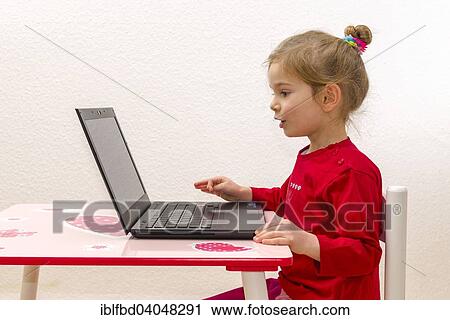 "Girl, 3 years, sitting at a table, using a laptop" View Large Photo Image Stock Image - "Girl, 3 years, sitting at a table, using a laptop". Fotosearch