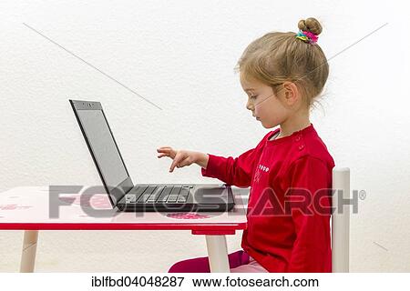 Stock Photo - "Girl, 3 years, sitting at a table, using a laptop". Fotosearch