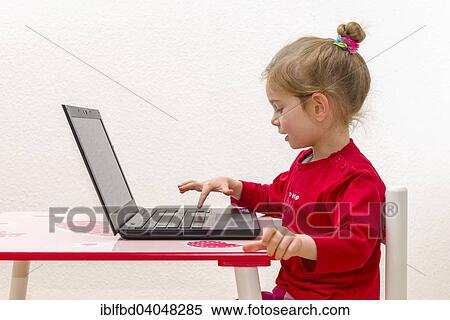 Stock Photography - "Girl, 3 years, sitting at a table, using a laptop". Fotosearch